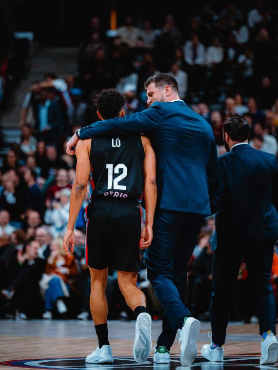 Courtside hospitality experience at a Paris Basketball game featuring Coach Tiago Splitter and player Maodo Lo, offering an exclusive view of the action