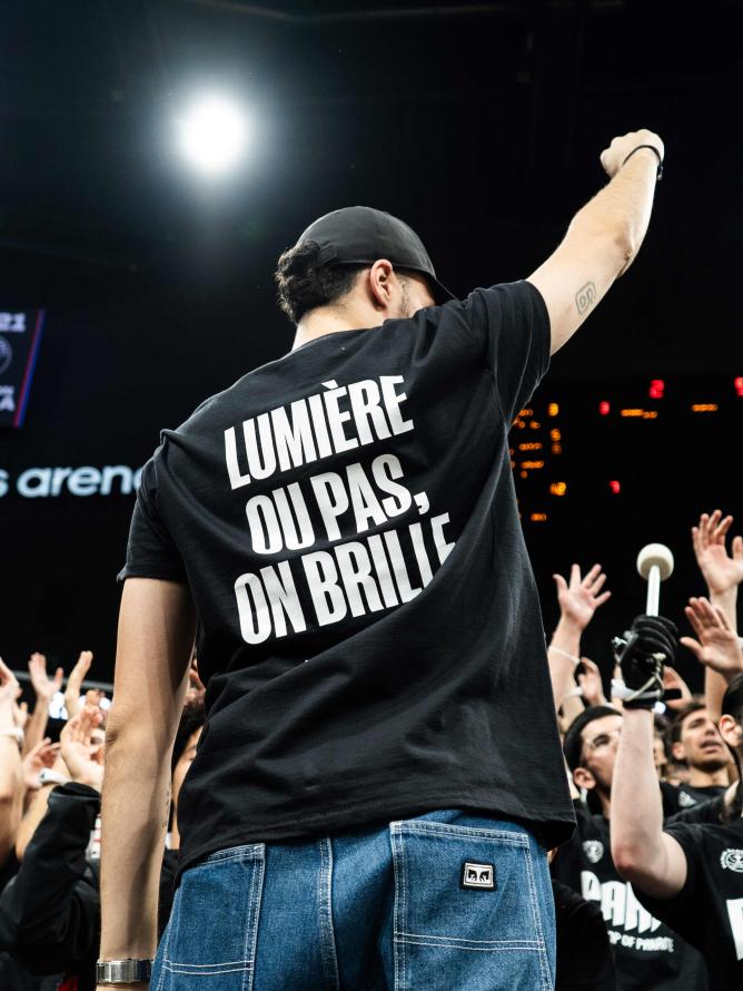 Paris Basketball supporters cheering at the Adidas Arena, showing team spirit and excitement during a game