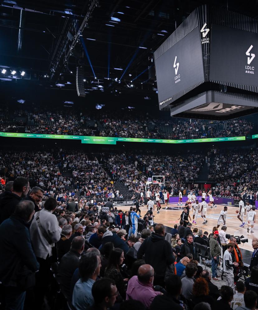 Salle de l'ASVEL Euroleague avec places hospitalités premium et joueurs en action sur le parquet